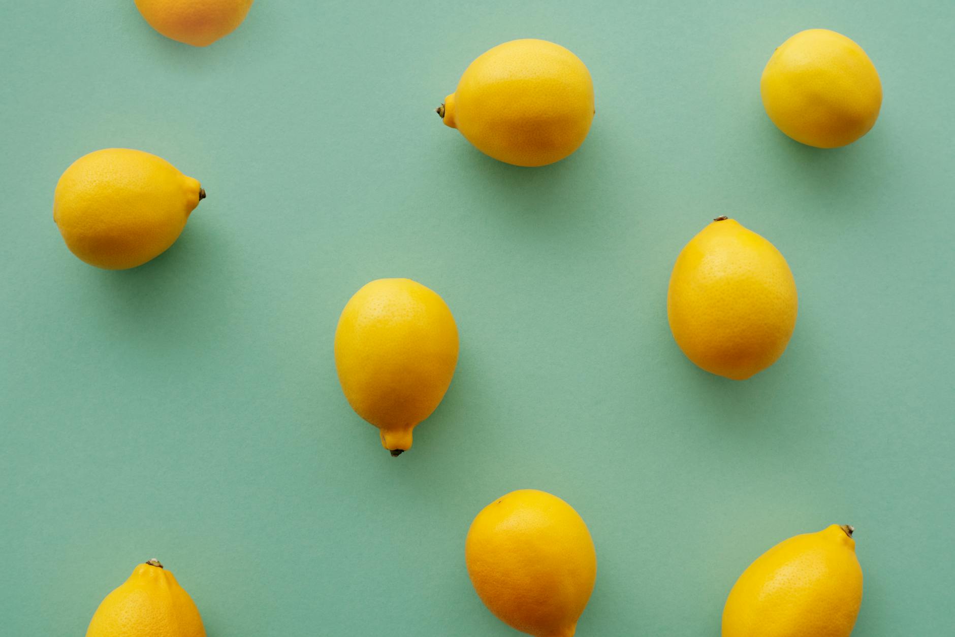 Bright yellow lemons arranged on a pastel green background, representing fresh pleasure and vitality.