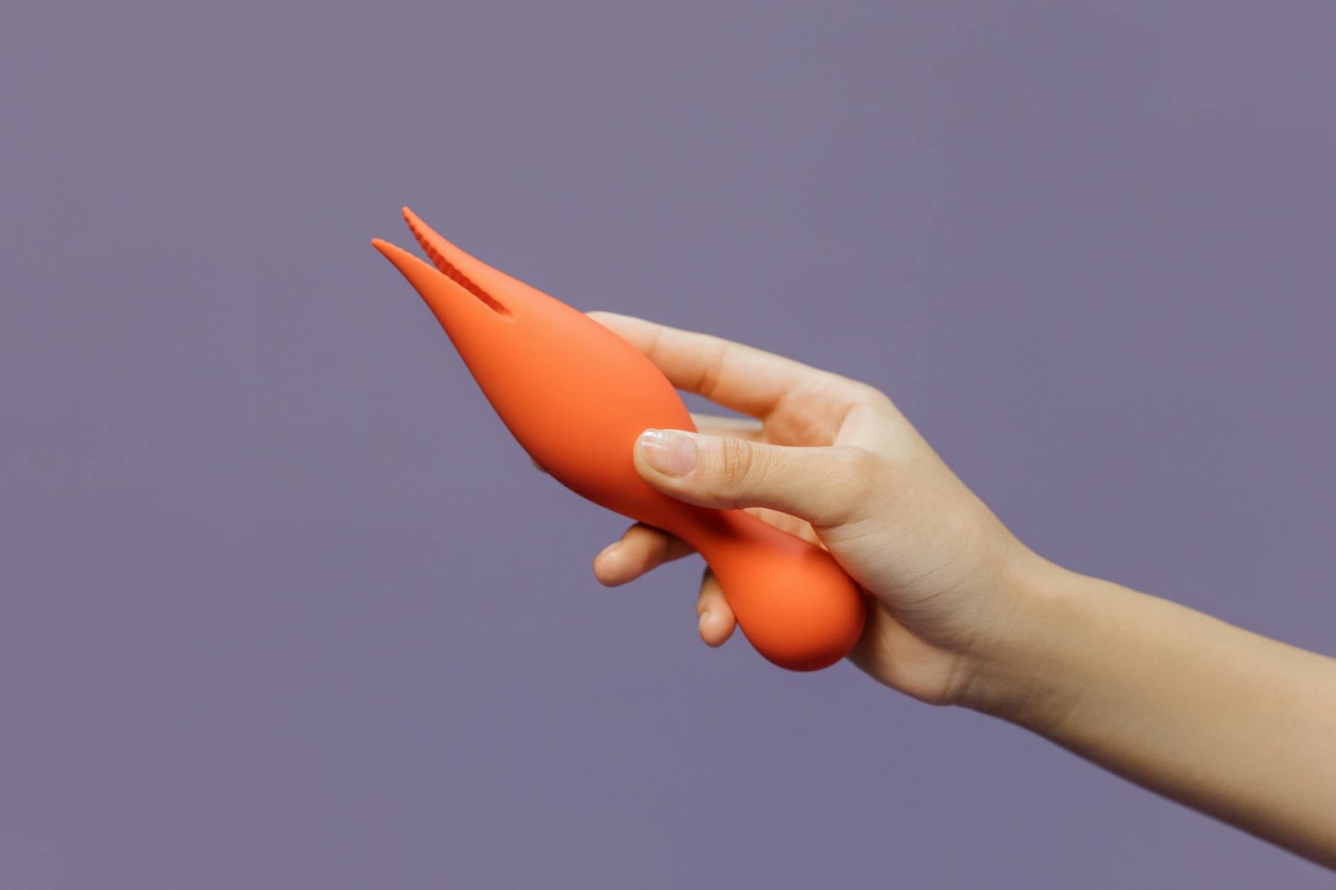 A hand holding a lemon vibrator against a minimalistic purple backdrop, showcasing sensuality and control.